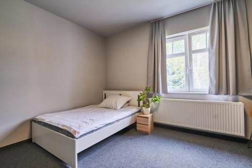 a white bedroom with a bed and a window at Motel ROKO in Szczecińska