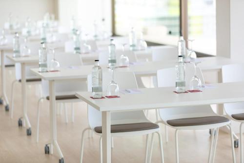 a row of white tables and chairs with bottles on them at Hotel Cristina by Tigotan Las Palmas - Adults Only in Las Palmas de Gran Canaria