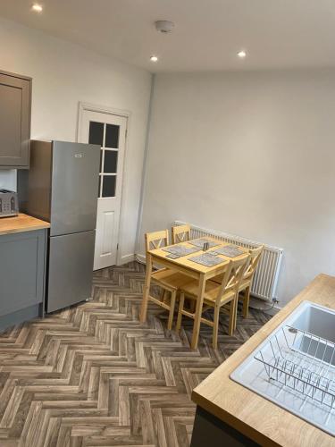 a kitchen with a table and chairs and a refrigerator at House In Padfield in Tintwistle