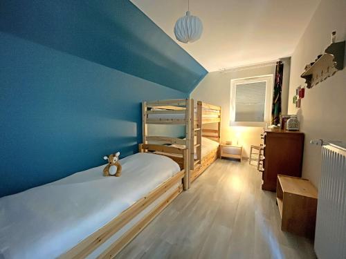une chambre avec deux lits superposés et un mur bleu dans l'établissement Charmante maison avec jardin, piscine et parking - FR-1-646-54, à Groffliers