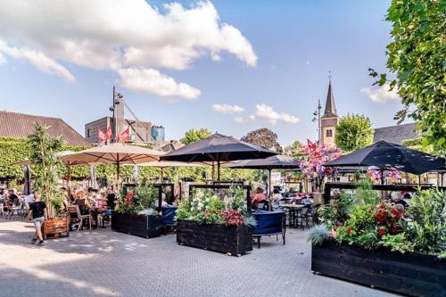 un patio con tavoli, sedie e ombrelloni di Villa June Rosy a Wijchen