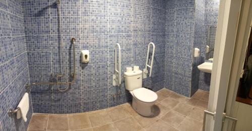 a blue tiled bathroom with a toilet and a sink at New Hortaleza Coliving in Madrid