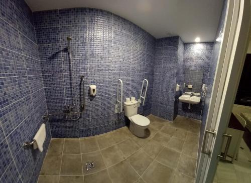 a blue tiled bathroom with a toilet and a sink at New Hortaleza Coliving in Madrid