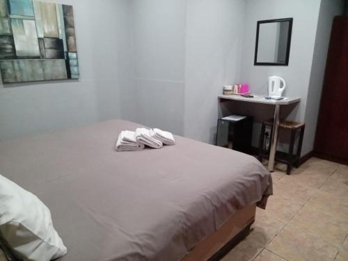 a bedroom with a bed with two towels on it at Grand Central Guesthouse in Rustenburg