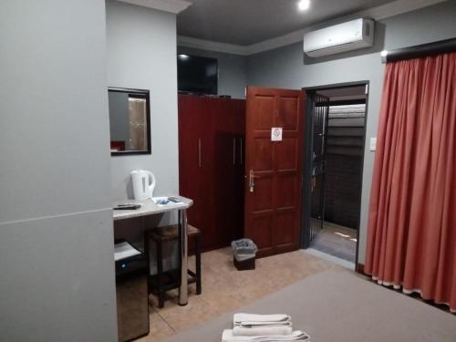 a room with a kitchen with a red curtain and a sink at Grand Central Guesthouse in Rustenburg
