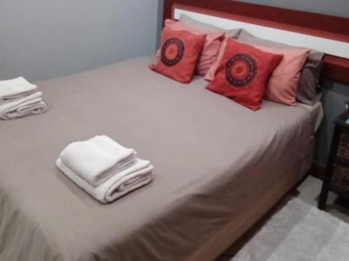 a bed with white towels and red pillows on it at Grand Central Guesthouse in Rustenburg