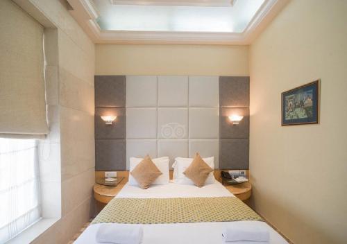sypialnia z łóżkiem z poduszkami i oknem w obiekcie Regent Hotel w Bombaju