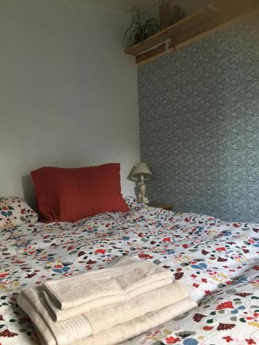 Una cama con toallas y una almohada roja. en Sjöstuga, Archipelago Beach House, en Värmdö