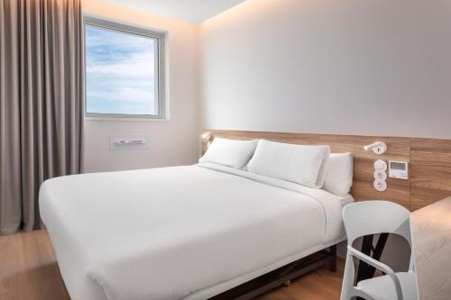 a white bed in a room with a window at B&B HOTEL Vila do Conde in Vila do Conde