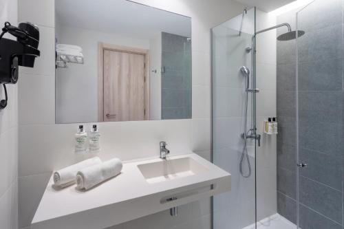 ein weißes Bad mit einem Waschbecken und einer Dusche in der Unterkunft B&B HOTEL Vila do Conde in Vila do Conde