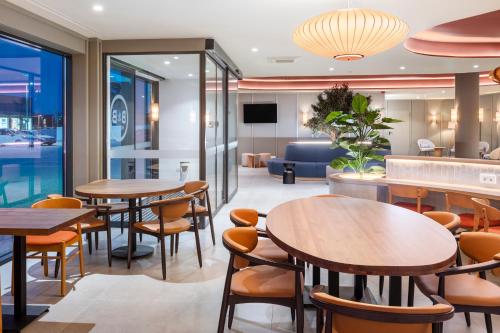 a restaurant with tables and chairs and a couch at B&B HOTEL Vila do Conde in Vila do Conde