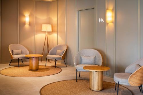 a waiting room with chairs and tables and a lamp at B&B HOTEL Vila do Conde in Vila do Conde
