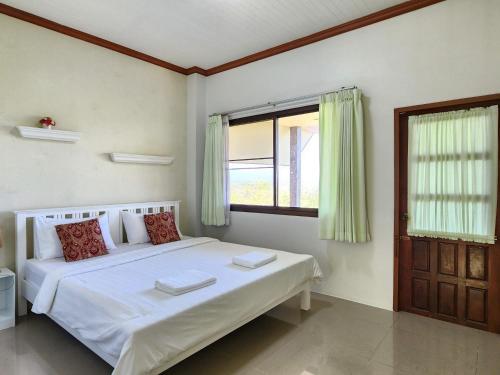 1 dormitorio con cama blanca y ventana en Phureya Ville, en Ban Map Khla