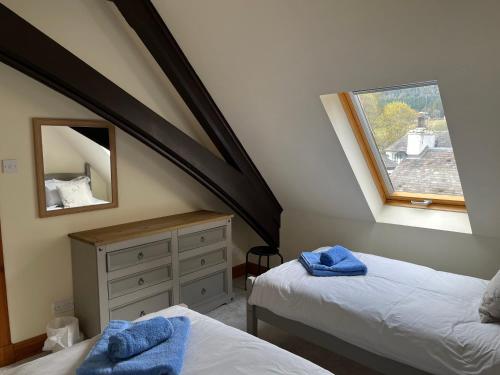 1 dormitorio en el ático con 2 camas y ventana en Lairds and Keepers Apartments, en Dunkeld