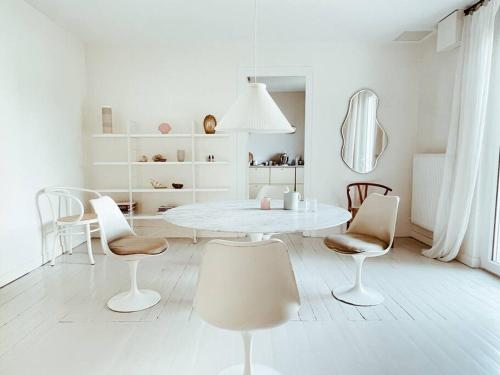 ein weißes Esszimmer mit einem weißen Tisch und Stühlen in der Unterkunft Charmante et lumineuse maison de ville 150 m2 in Andrézieux-Bouthéon
