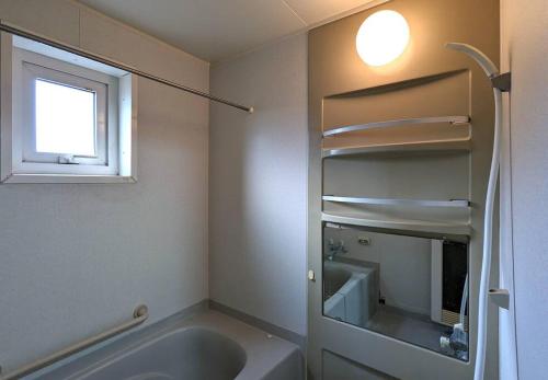 ein Bad mit einer Badewanne, einem Waschbecken und einem Fenster in der Unterkunft Beach Front Fugoppe - spacious & sunny in Yoichi
