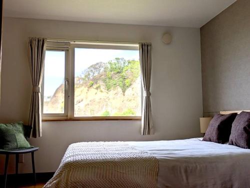ein Schlafzimmer mit einem Bett und einem großen Fenster in der Unterkunft Beach Front Fugoppe - spacious & sunny in Yoichi
