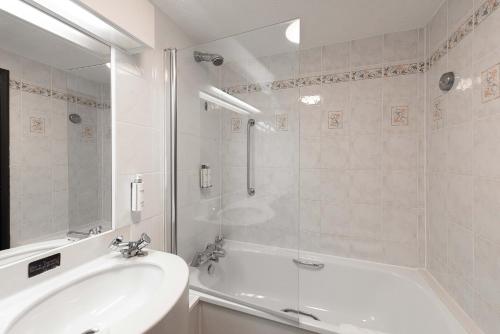 a white bathroom with a tub and a sink at Village Hotel Liverpool in Prescot