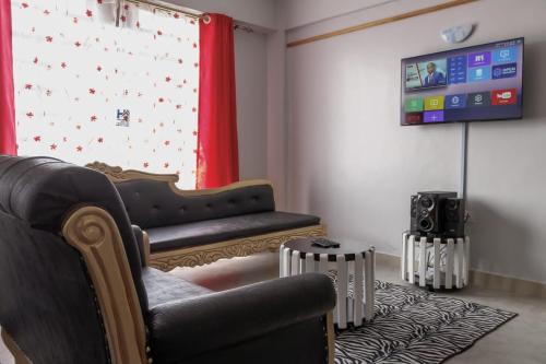 - un salon avec un canapé et une télévision dans l'établissement Hyrax Hill Residence, Nakuru, à Nakuru