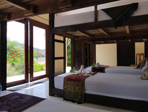 two beds in a room with a view of a field at Dorm Riverside in Pakbeng