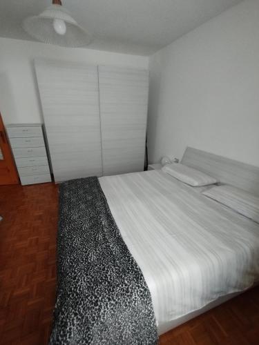 ein Schlafzimmer mit einem großen weißen Bett und einem Schrank in der Unterkunft Ca Bellavista in Chiesa in Valmalenco