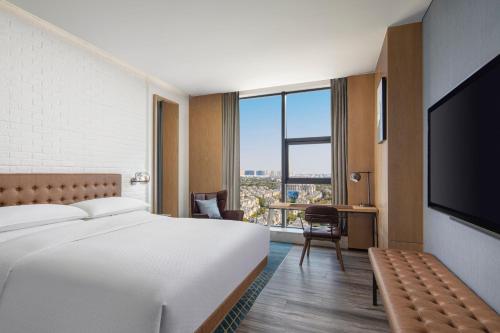 Four Points by Sheraton Shanghai Hongqiao في شانغهاي: غرفة فندقية بسرير وتلفزيون بشاشة مسطحة