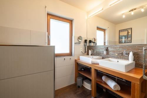 a bathroom with two sinks and a refrigerator at Arch San Martin C in Scuol