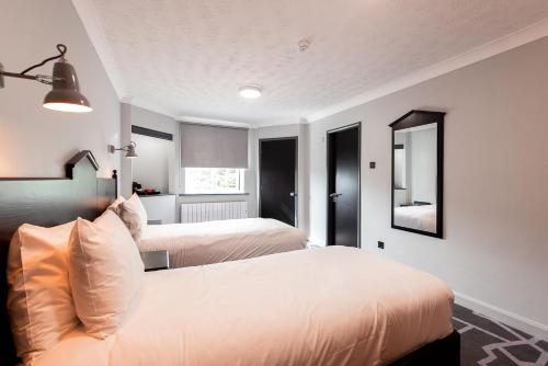 a bedroom with two beds and a mirror at Village Hotel Liverpool in Prescot