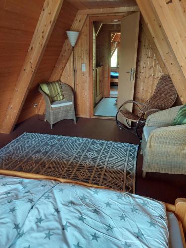 a room with a bed and chairs in a attic at Haus am See Willingen in Willingen