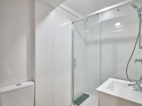 uma casa de banho branca com um chuveiro e um lavatório. em NEW Plaza Elíptica Metro Bus 15 min centro 3d Luxe reformado em Madri