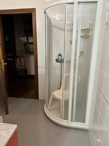 Una ducha de cristal con una silla blanca. en B & B DELLE VAUDE en Front