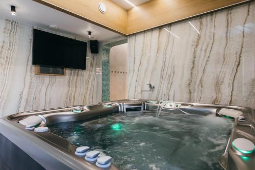 a bath tub with a television in a bathroom at NOZON Apartments & Wellness in Odorheiu Secuiesc