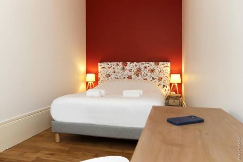 een slaapkamer met een wit bed en een houten tafel bij La Chouette in Dijon