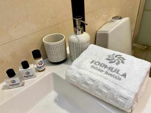 a bathroom sink with a towel and a soap dispenser at Mar e Sol by - T3 , wi-fi e estacionamento in Quarteira