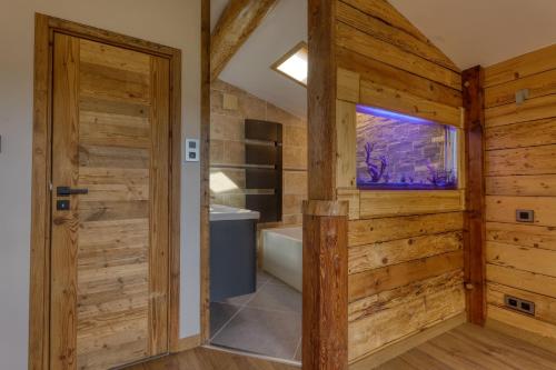 La salle de bains est pourvue de murs en bois, d'une baignoire et d'une fenêtre. dans l'établissement *Nouveau* Chalet Chamonix Cottage, à Chamonix-Mont-Blanc