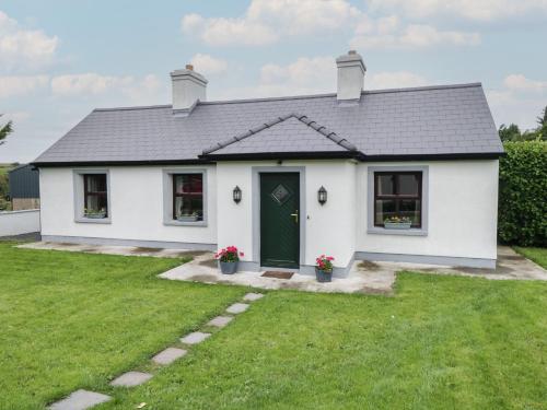 a white house with a green door and a yard at Kate's Cottage in Westport