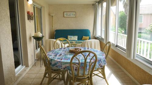 una sala da pranzo con tavolo, sedie e finestre di Appartement avec piscine proche de la mer a La Londe-les-Maures