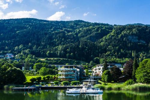 a couple of boats on a lake with a mountain at Apart Hotel Legendär in Steindorf am Ossiacher See