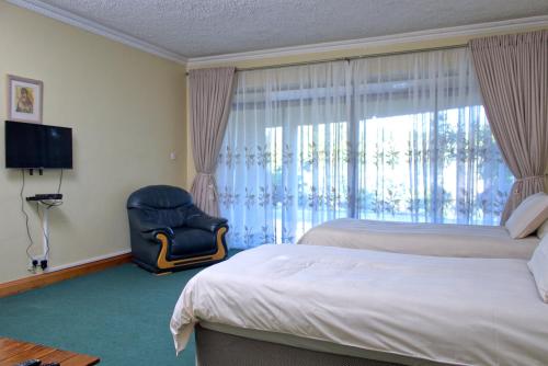 um quarto de hotel com uma cama e uma cadeira e uma janela em Unique Bed and Breakfast em Harare