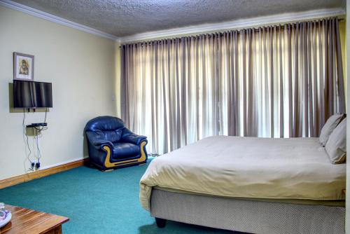 a bedroom with a bed and a chair and a window at Unique Bed and Breakfast in Harare