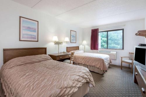a hotel room with two beds and a desk at Super 8 by Wyndham Groton in Groton