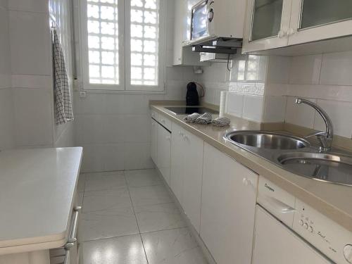 a kitchen with white cabinets and a sink and a counter at Gorliz Beach House in Górliz-Elexalde