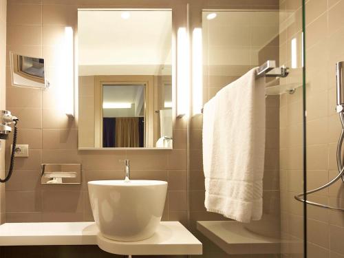 ローマにあるメルキュール ローマ セントロ コロッセオのバスルーム(トイレ、洗面台、鏡付)