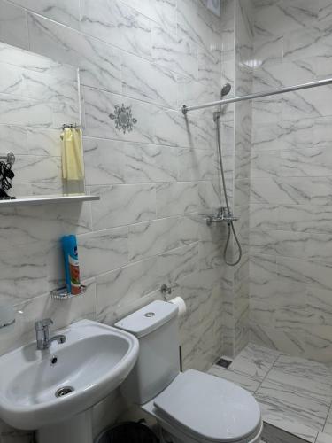 Baño blanco con aseo y lavamanos en Отель Гудоу, en Gudauta