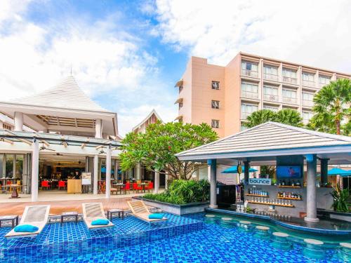 a swimming pool with chairs and a hotel at Grand Mercure Phuket Patong in Patong Beach