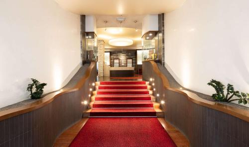 un pasillo con alfombra roja y escaleras con luces en Best Western Gorizia Palace en Gorizia