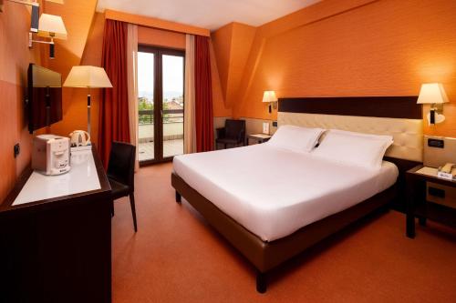 Habitación de hotel con cama, escritorio y ventana en Best Western Gorizia Palace en Gorizia