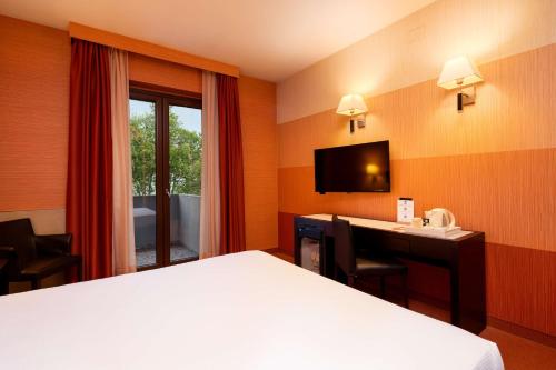 a hotel room with a bed and a desk and a television at Best Western Gorizia Palace in Gorizia