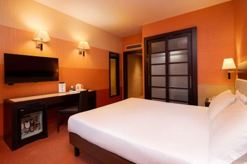 a hotel room with a bed and a desk and a television at Best Western Gorizia Palace in Gorizia