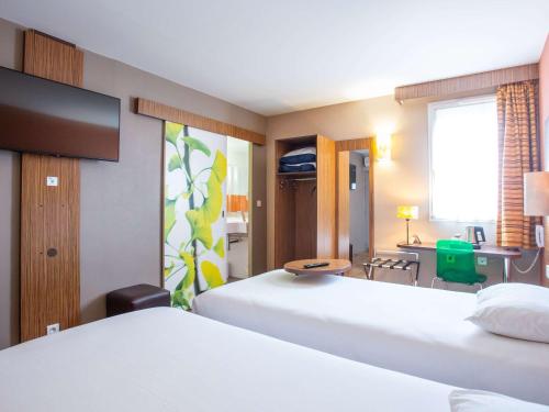 a hotel room with two beds and a desk at ibis Styles Bourges in Bourges